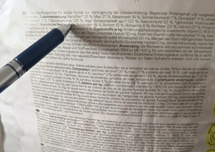 Stift zeigt auf die Deklaration eines Hundefutters mit Zusammensetzung und analytischen Bestandteilen.